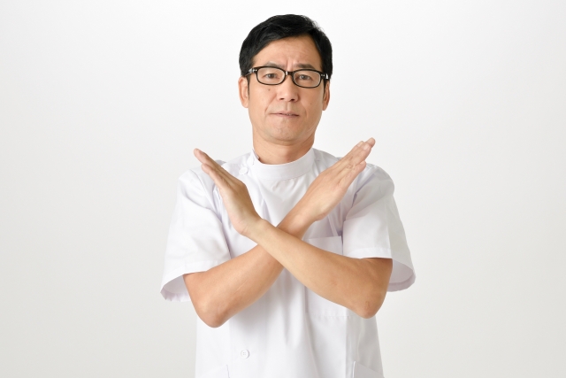 手で×マーク作る整骨院院長